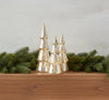 Set of three silver Christmas tree-shaped decorations with lights on a wooden mantle with garland.