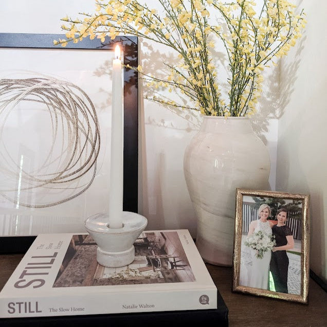 Decorative setup with a vase of yellow flowers, a book titled 'Still', and a framed photo on a surface.