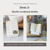 Marble cookbook holder with a cookbook on a kitchen counter.
