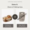 Choice between a handwoven bread basket and a beige marble serving board for 'Golden Hour: Summer Abode Box'.