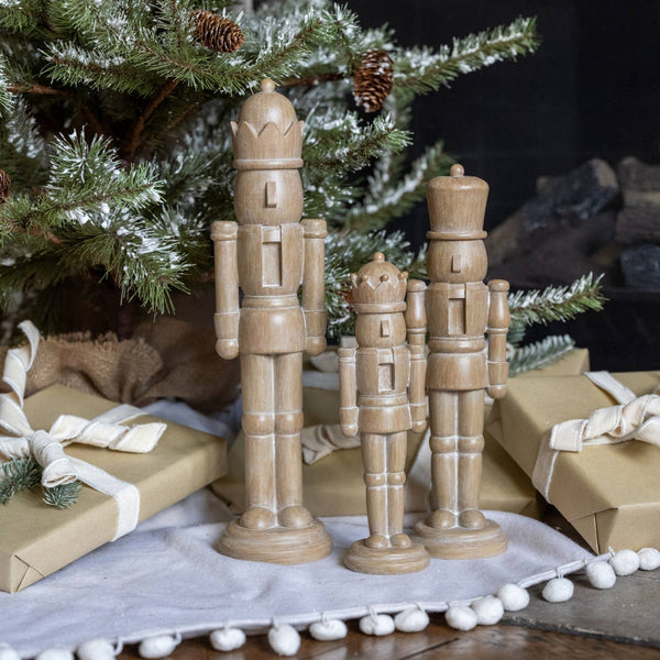 Wooden nutcrackers on a Christmas setting with presents and tree.