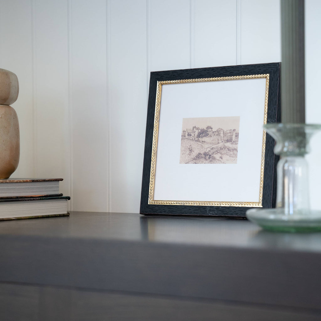 Framed artwork on a shelf with decorative items