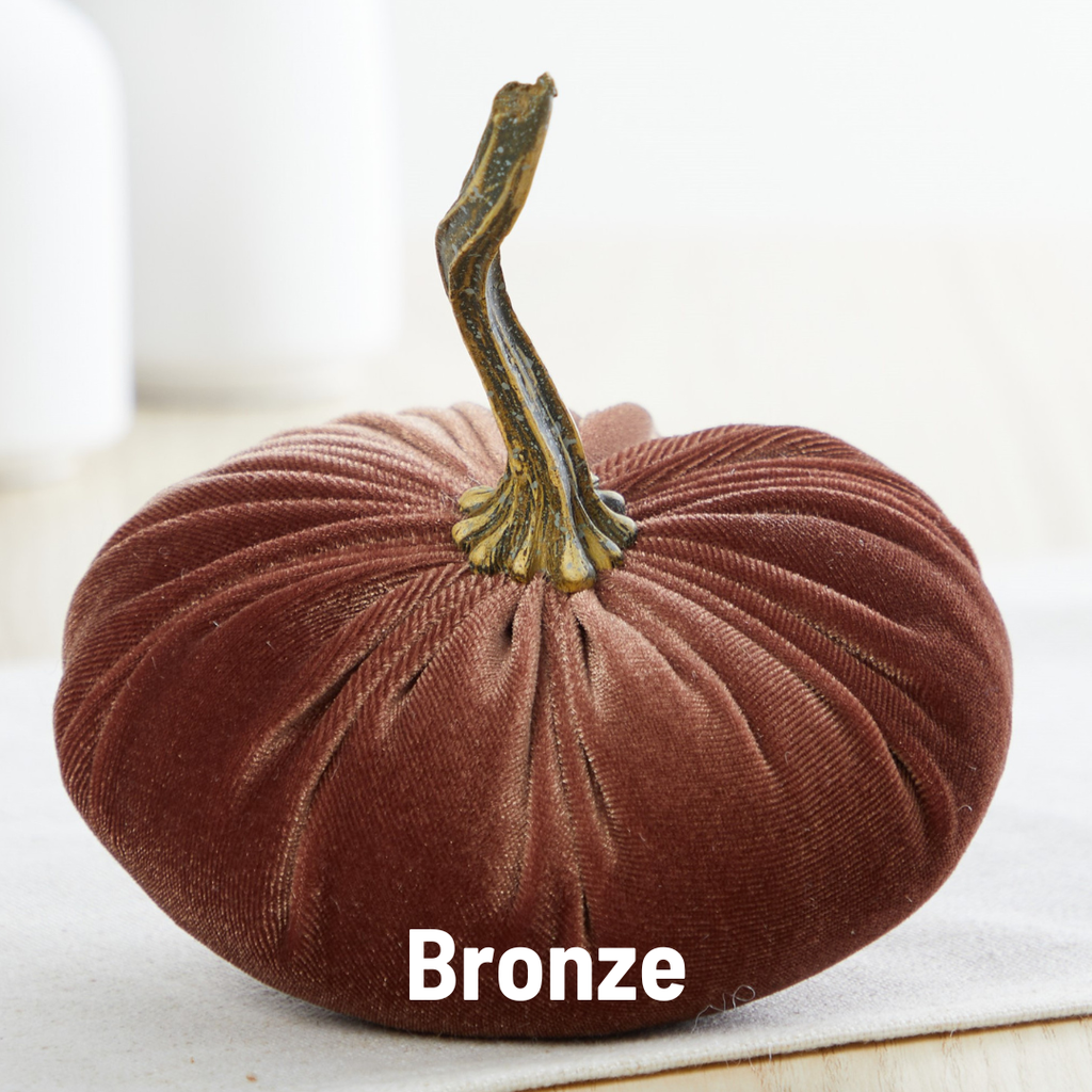 A small velvet pumpkin with a realistic resin stem, bronze in color, displayed on a textured background.