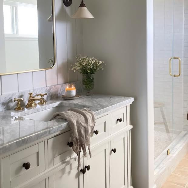 Bathroom with marble countertop, sink, and white cabinets.