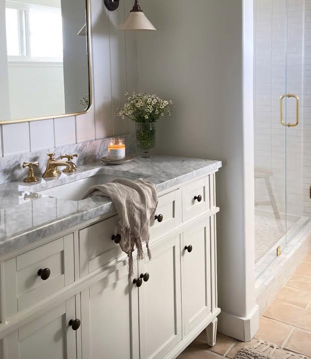 Bathroom with marble countertop, sink, and white cabinets.