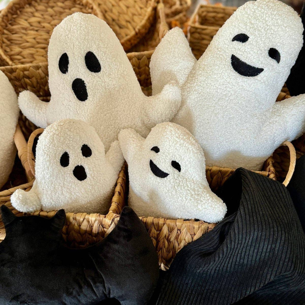 White ghost sherpra pillow in a woven basket with a black cat and dark fabric in the background