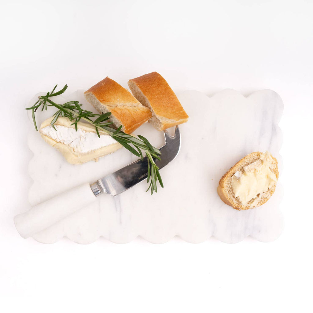 Slices of bread with butter and rosemary on a marble surface with a knife.