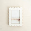 White scalloped picture frame on a beige textured wall