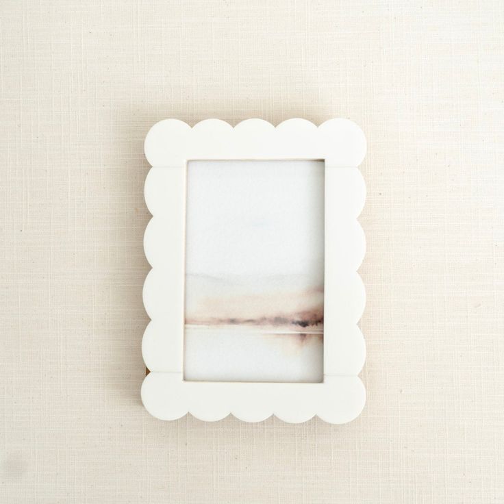 White scalloped picture frame on a beige textured wall