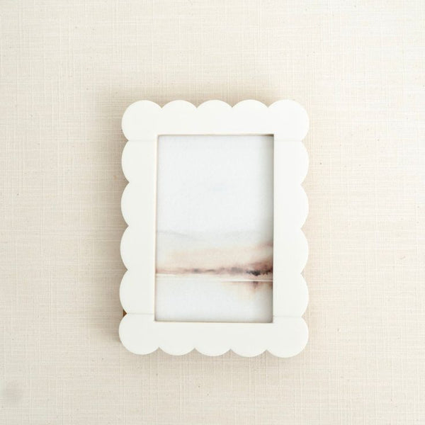White scalloped picture frame on a beige textured wall
