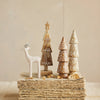 Decorative wooden trees and deer figurines on a textured surface with a neutral background