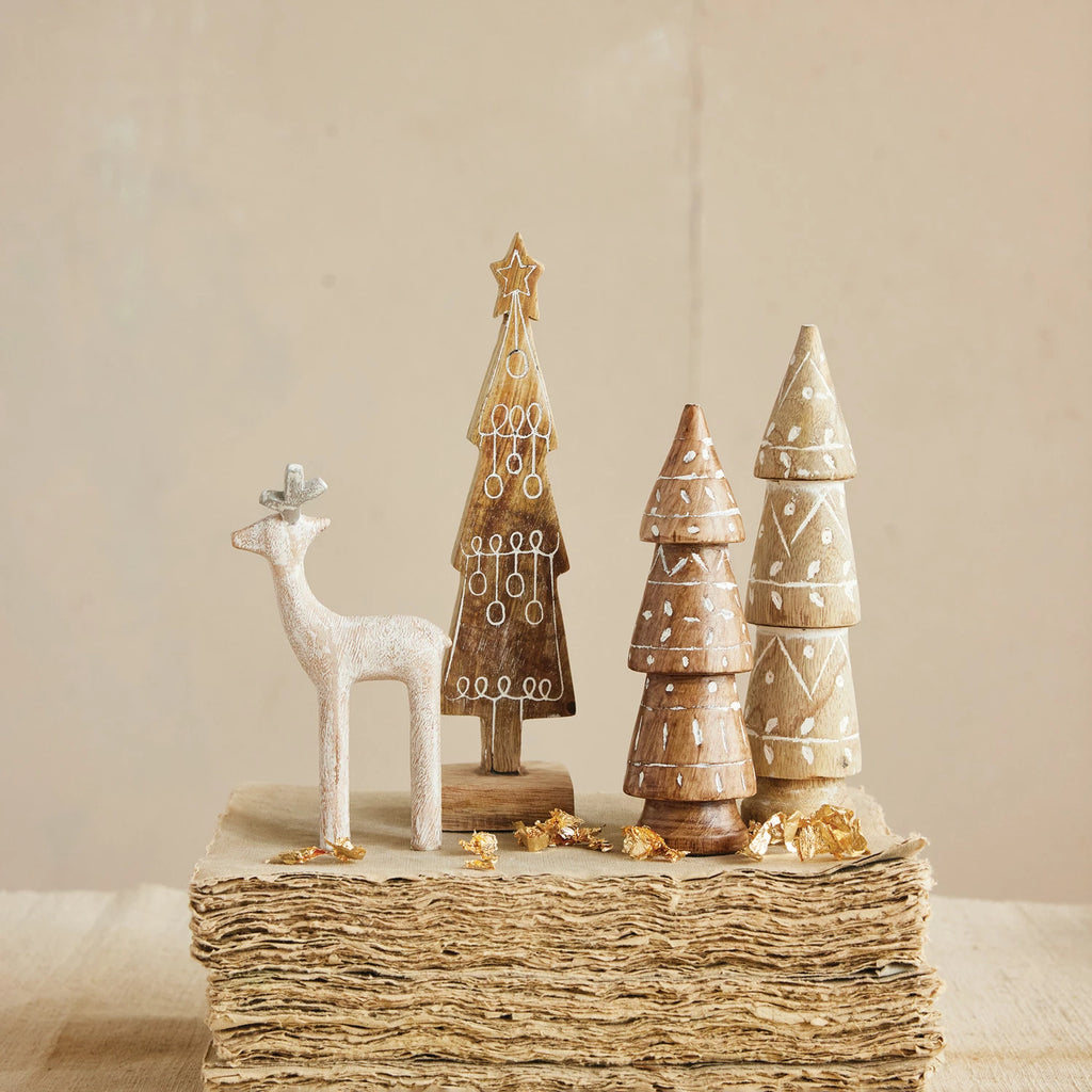 Decorative wooden trees and deer figurines on a textured surface with a neutral background