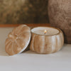 Wooden pumpkin-shaped candle holder with a lit candle on a neutral background