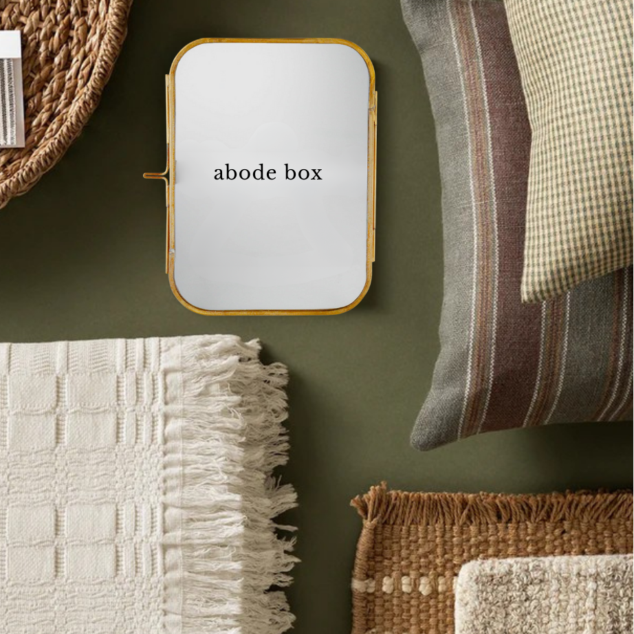 Decorative items including a textured blanket, pillows, and a brass picture frame on a green surface.