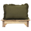 An olive green ruffled lumbar pillow displayed on a rustic wooden bench against a solid white background.