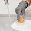 person washing dish with bamboo dish brush