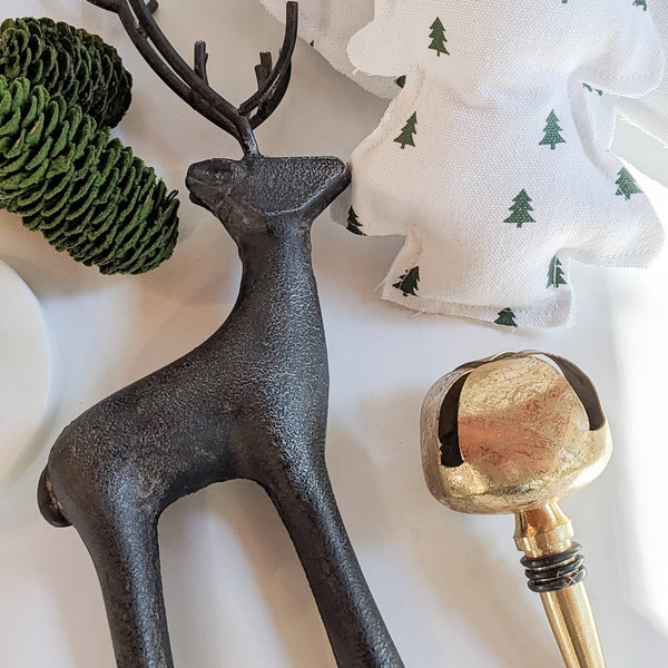 Decorative Reindeer Figurine paired with christmas decorations on a white background. 