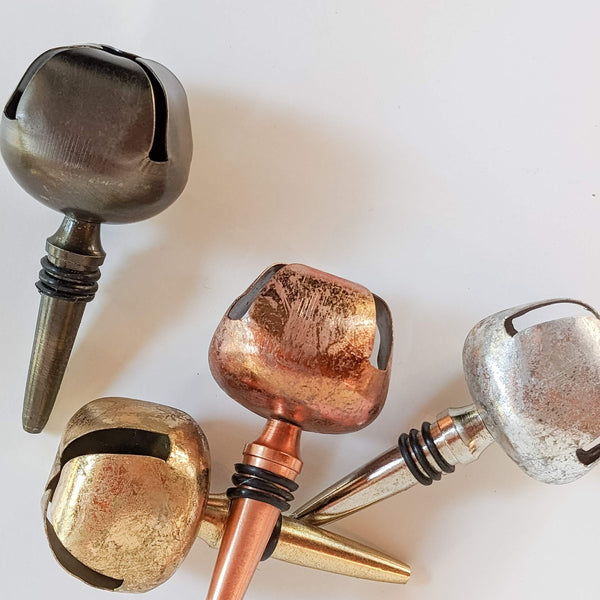A collection of wine bottle stoppers with decorative bell-shaped tops in various colors.