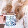 woman holding blue and white coffee mug