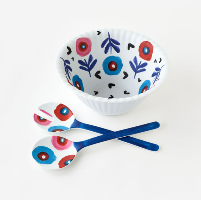 A white melamine serving bowl with a floral pattern, accompanied by two matching serving utensils, against a neutral background.