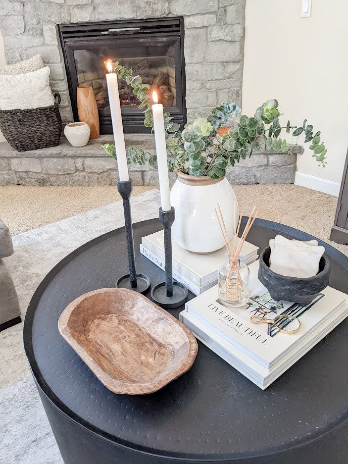 wooden dough bowl and modern black candle holders on coffee table